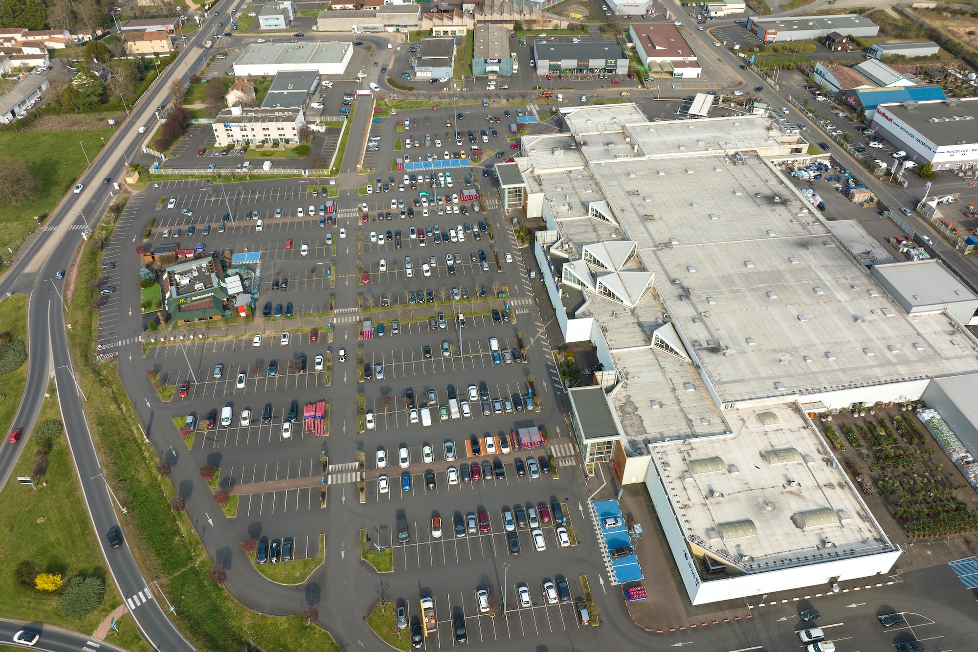 Aerial view of many colorful cars parked on parking lot with lines and markings for parking places
