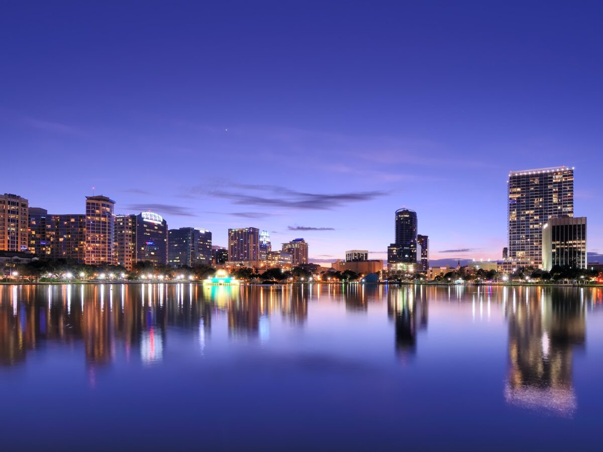 City skyline reflected in calm water at dusk.
