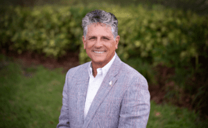 Gray-haired man smiling in striped blazer