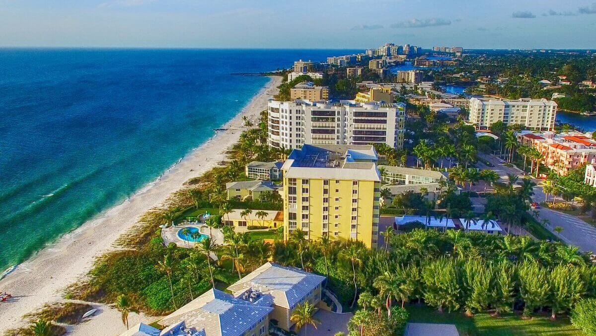 A view of the beach from above shows palm trees, buildings and ocean.