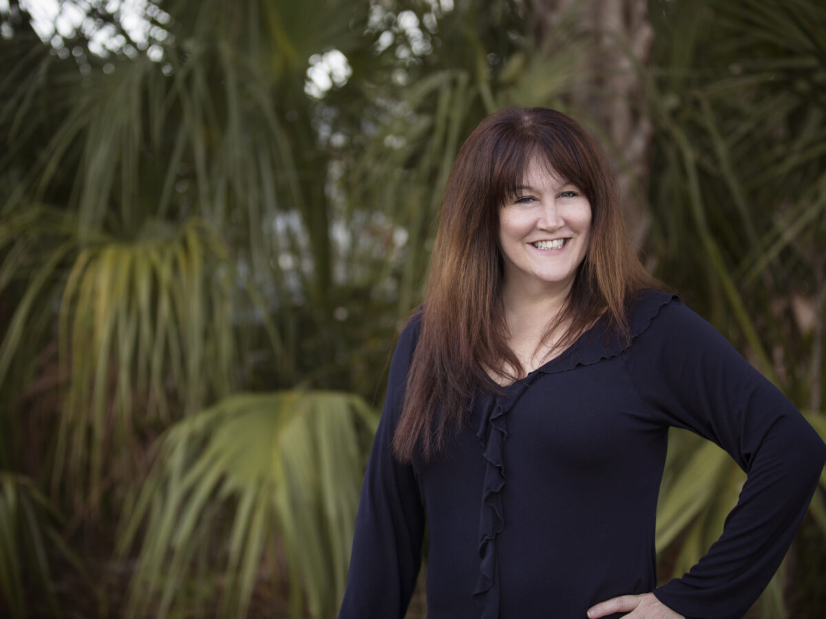 A woman standing in front of some trees