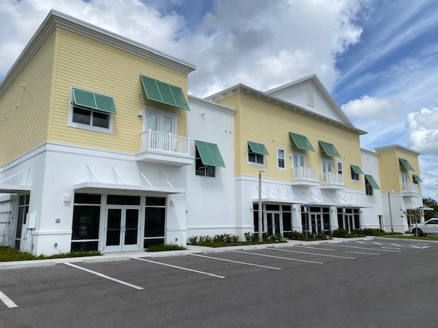 Yellow and white building with green awnings.