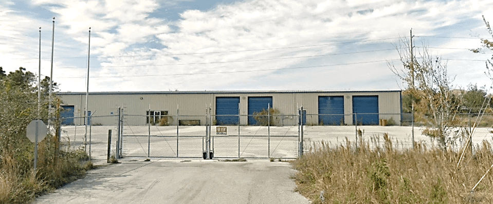 Warehouse with blue doors behind a fence.