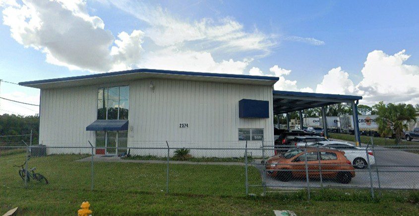 Warehouse building with cars parked outside.