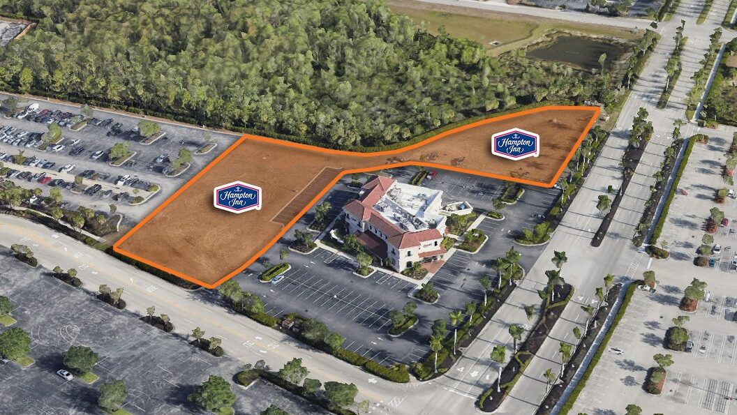 Aerial view of parking lot and wooded area.