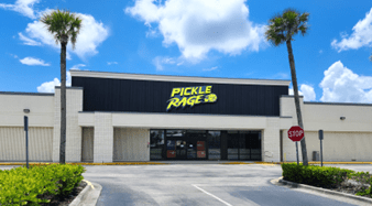 Storefront with "Pickle Rage" sign and palm trees.