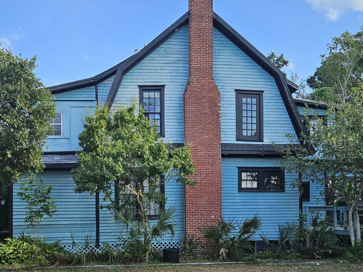Blue two-story house with red brick chimney