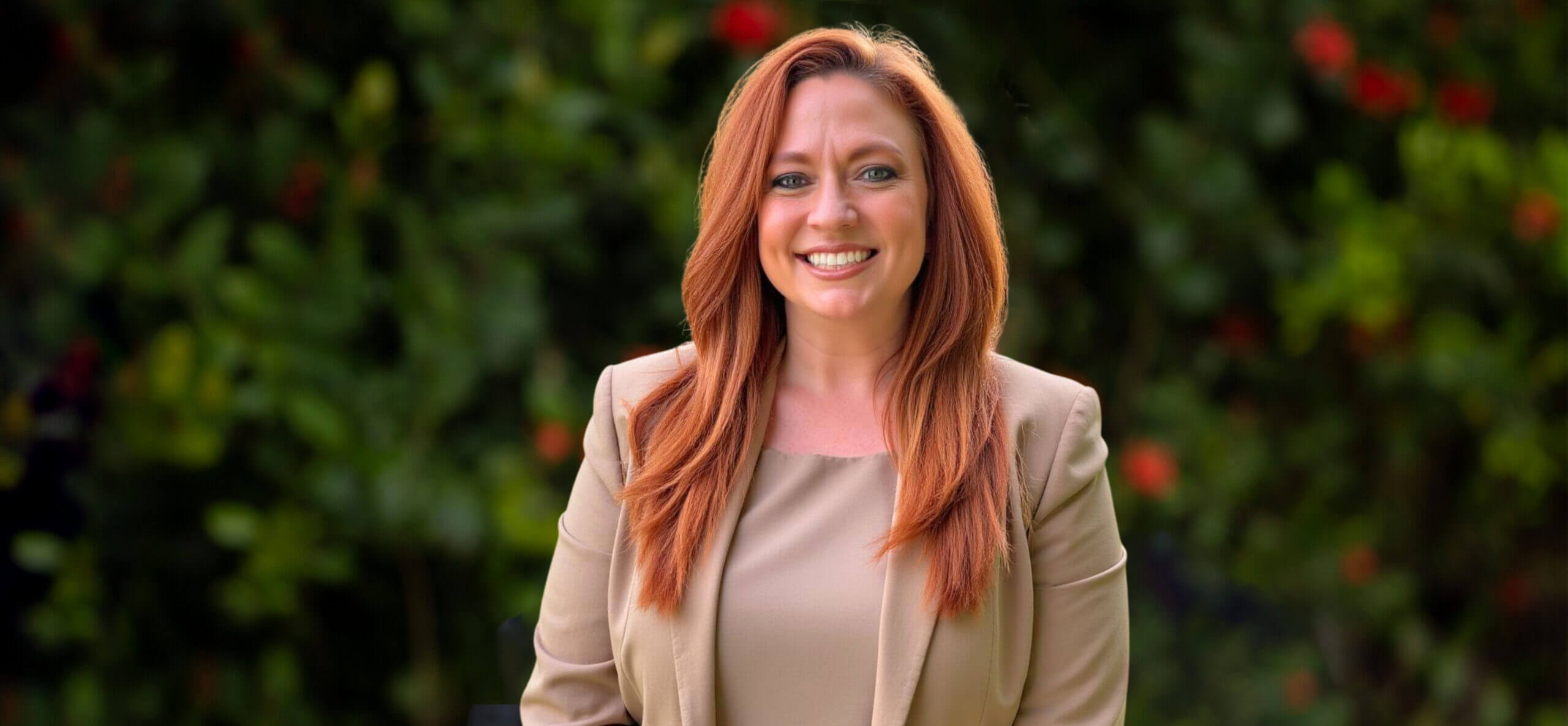 Smiling red-haired woman in beige blazer