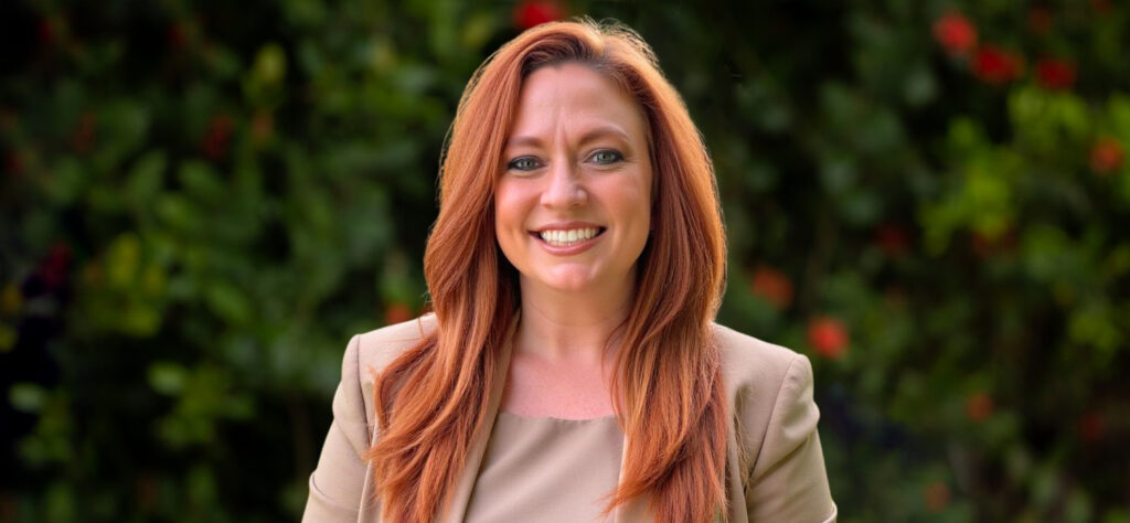 Outdoor headshot of smiling red-haired woman