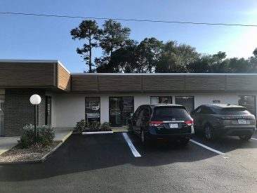 Single-story office storefront with parked SUVs