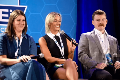 Three panelists laughing on conference stage